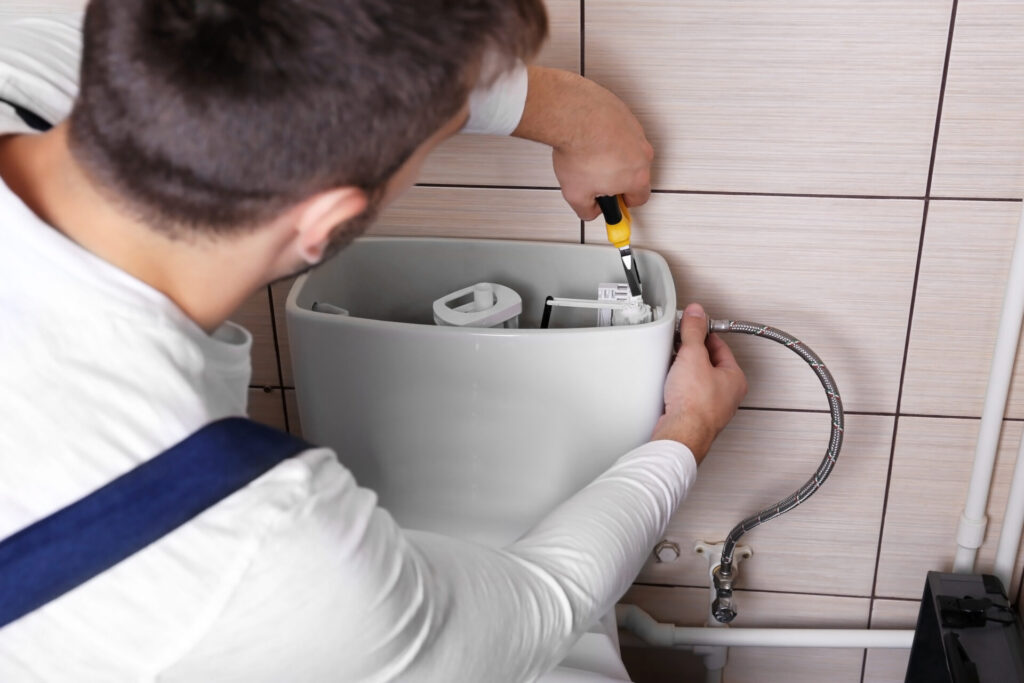 Plumber Repairing Toilet in Bathroom